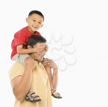 Royalty Free Photo of a Boy Sitting on His Father's Shoulders With Hands Over His Eyes 