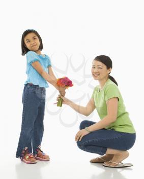 Royalty Free Photo of a Girl Handing a Bouquet of Flowers to Her Mother