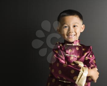 Royalty Free Photo of a Boy Standing Against a Black Background in Traditional  Attire