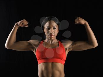 Muscular African American woman looking at viewer with biceps flexed.