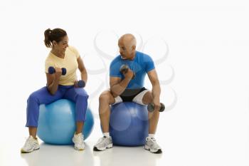 Royalty Free Photo of a Man and Woman Balancing on Exercise Balls While Working Out With Dumbbells