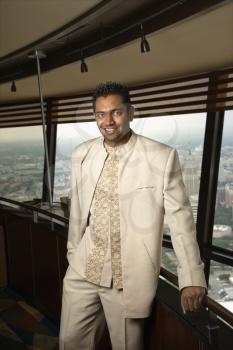 Royalty Free Photo of a Portrait of an Indian  Man Standing Near a Window in a Tower Restaurant Smiling