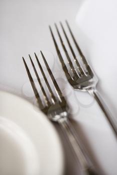 Royalty Free Photo of a Salad Fork and Dinner Fork With a Plate on a White Table Cloth