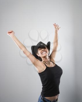 Royalty Free Photo of a Portrait of a Pretty Woman in a Cowboy Hat an Holding Her Arms Up in the Air