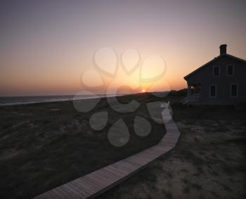 Royalty Free Photo of Sunset Over a Coastal Beach House With a Wooden Boardwalk at Bald Head Island, North Carolina