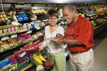 Royalty Free Photo of a Couple in a Grocery Store Smiling and Pointing at a Shopping List