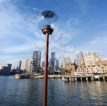 Royalty Free Photo of a Lamppost in Sydney Cove with City Skyline and Water in Sydney, Australia