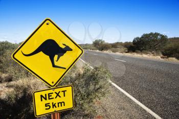 Royalty Free Photo of a Kangaroo Crossing Sign by a Road in Rural Australia