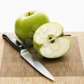 Royalty Free Photo of a Still Life of Green Apples and a Knife on a Cutting Board