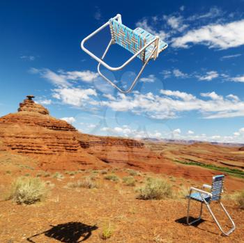 Royalty Free Photo of One Lawn Chair on the Ground and Other Up in the Air in a Desert Landscape