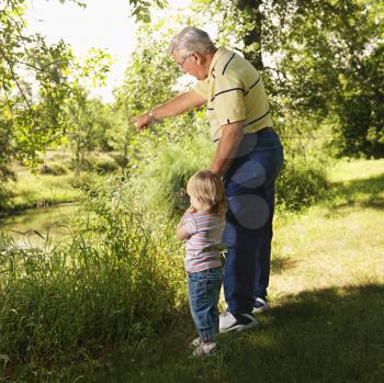Royalty Free Photo of a Grandfather Holding Granddaughter's Hand by a Creek