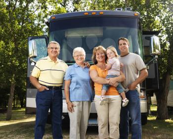 Royalty Free Photo of a Portrait of a Three Generation Family Standing in Front of a Recreational Vehicle Smiling