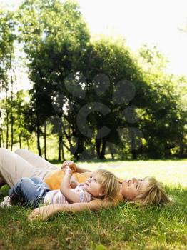 Royalty Free Photo of a Mother with Toddler Daughter Lying in the Grass at Park Relaxing