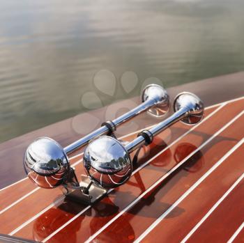 Royalty Free Photo of a Detail of Dual Chrome Trumpet Horns on a Wooden Boat Floating in Water