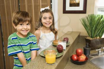 Royalty Free Photo of a Brother and Sister Sitting at a Kitchen Counter with a Healthy Breakfast