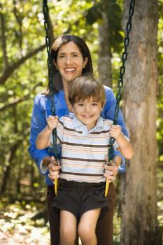 Royalty Free Photo of a Mother Pushing Her Son on a Swing 