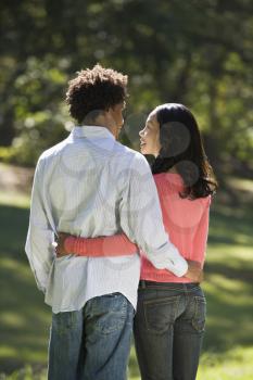 Royalty Free Photo of a Rear View of a Couple Standing in a Park With Arms Around Each Other