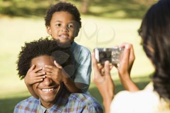 Royalty Free Photo of a Woman Photographing Husband and Son in a Park with a Digital Camera