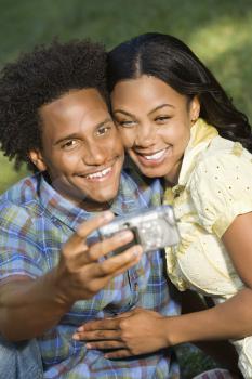 Royalty Free Photo of a Happy Smiling Couple Taking Pictures Together in a Park With a Digital Camera