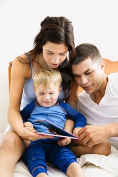 Royalty Free Photo of Parents Reading to Their Toddler Son in Bed