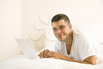 Royalty Free Photo of a Man Lying in Bed on a Laptop