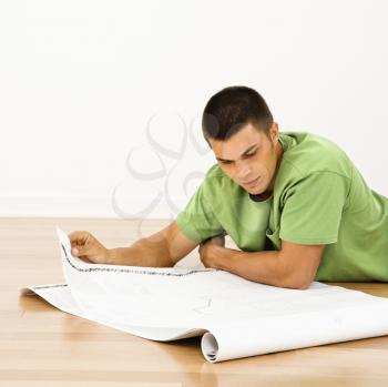 Royalty Free Photo of a Man Lying on the Floor in a Home Reading House Plans