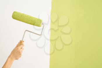 Royalty Free Photo of a female hand holding paint roller next to wall half painted
