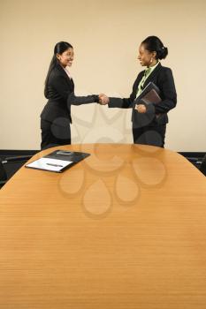 Royalty Free Photo of Two Businesswomen in Suits Shaking Hands and Smiling