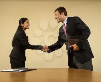 Royalty Free Photo of Two Businesspeople in Suits Shaking Hands and Smiling