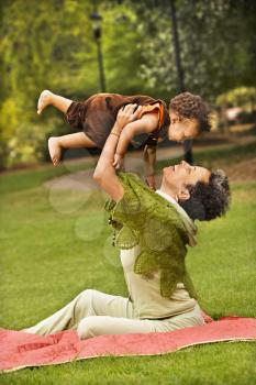 Royalty Free Photo of a Mother Holding Her Toddler Son Up in the Air and Smiling in the Park