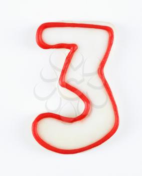 Royalty Free Photo of a Sugar Cookie in the Shape of a Number Three Outlined in Red Icing