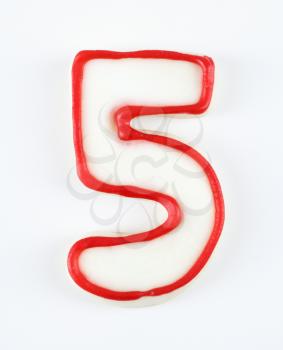 Sugar cookie in the shape of a number five outlined in red icing.