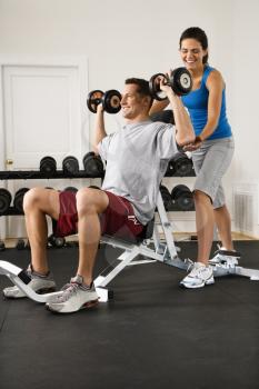 Royalty Free Photo of a Woman Assisting a Man Lifting Weights at a Gym