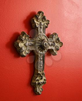 Royalty Free Photo of an Ornate Religious Cross Hanging on a Red Wall