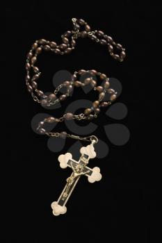 Christian rosary beads with crucifix on black background.