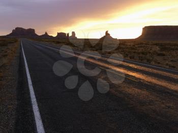 Royalty Free Photo of a Sunset Landscape of a Highway in Monument Valley on the border of Arizona and Utah, United States