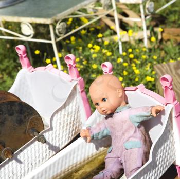 Royalty Free Photo of an Old Discarded Baby Doll Lying in a Crib in a Junkyard Field