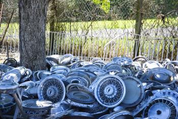 Royalty Free Photo of Stacks of Old Hubcaps on the Ground Next to a Tree