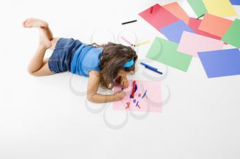 Young latino girl coloring on construction paper.