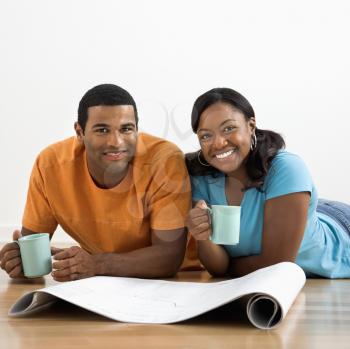 Royalty Free Photo of a Couple Looking at Blueprints and Drinking Coffee