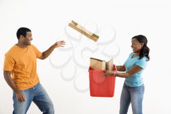 Royalty Free Photo of a Woman  Holding a Recycling Bin While a Man Tosses Cardboard Into It