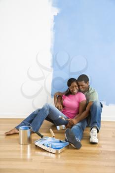 Royalty Free Photo of a Couple Sitting and Relaxing By a Half Painted Wall