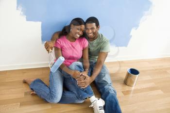 Royalty Free Photo of a Couple Sitting and Relaxing By a Half Painted Wall