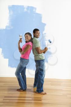 Royalty Free Photo of a Couple Standing Back to Back Holding Paintbrushes 