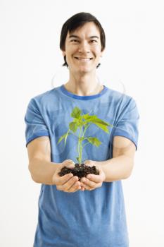 Royalty Free Photo of a Man Standing Holding a Cayenne Plant