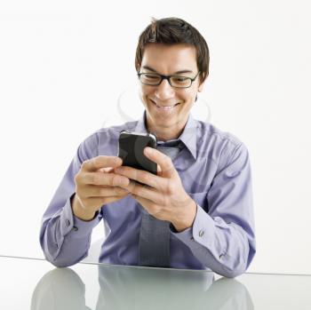 Royalty Free Photo of a Businessman Sitting at a Desk Texting Using His PDA Cellphone