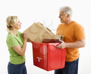 Royalty Free Photo of a Man Holding a Recycling Bin While a Woman Places Cardboard Into It