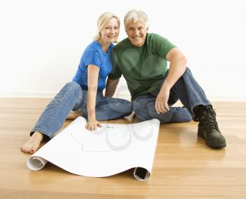 Royalty Free Photo of a Couple Sitting on the Floor with Architectural Blueprints