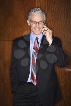 Businessman smiling while talking on his mobile phone. Vertical shot.