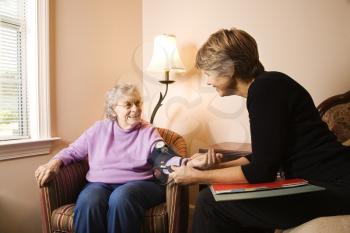 Nurse checks an elderly woman's blood pressure in an assisted living home.  Horizontal shot.